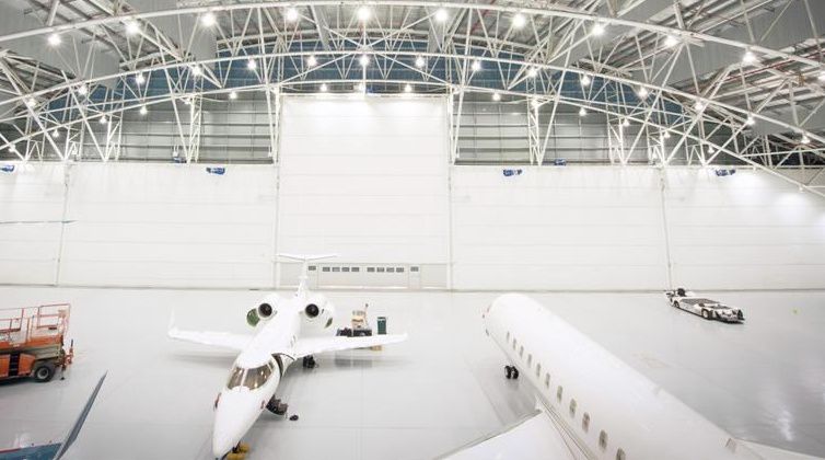 hangar de aeropuerto, con dos aviones blancos y cinco puertas blancas de hangar