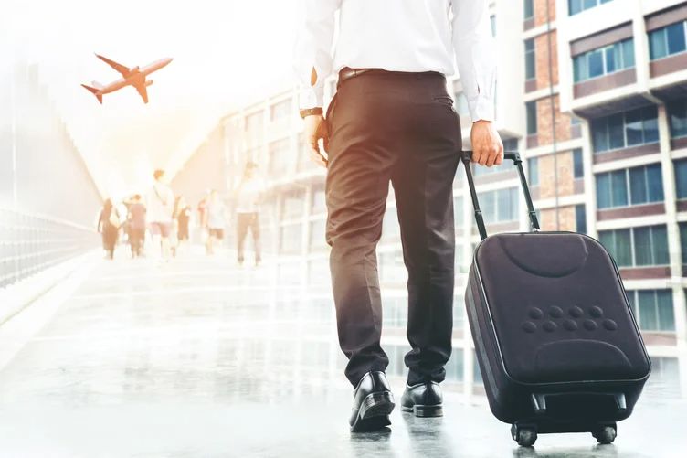 A businessman with luggage walking through an airport terminal, ready for his next business trip.