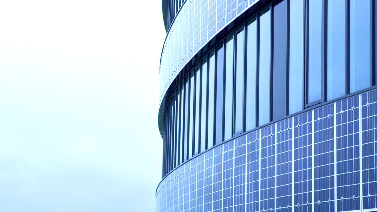 Close-up van de gevel van een rond gebouw met veel ramen.