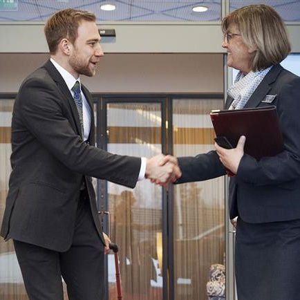 dve osebi se rokujeta pred avtomatskimi drsnimi vrati