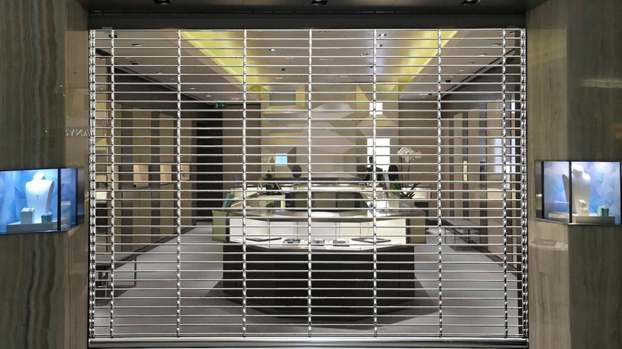 Vitrine d'une boutique de bijoux avec une grille à tubes droits fermée.