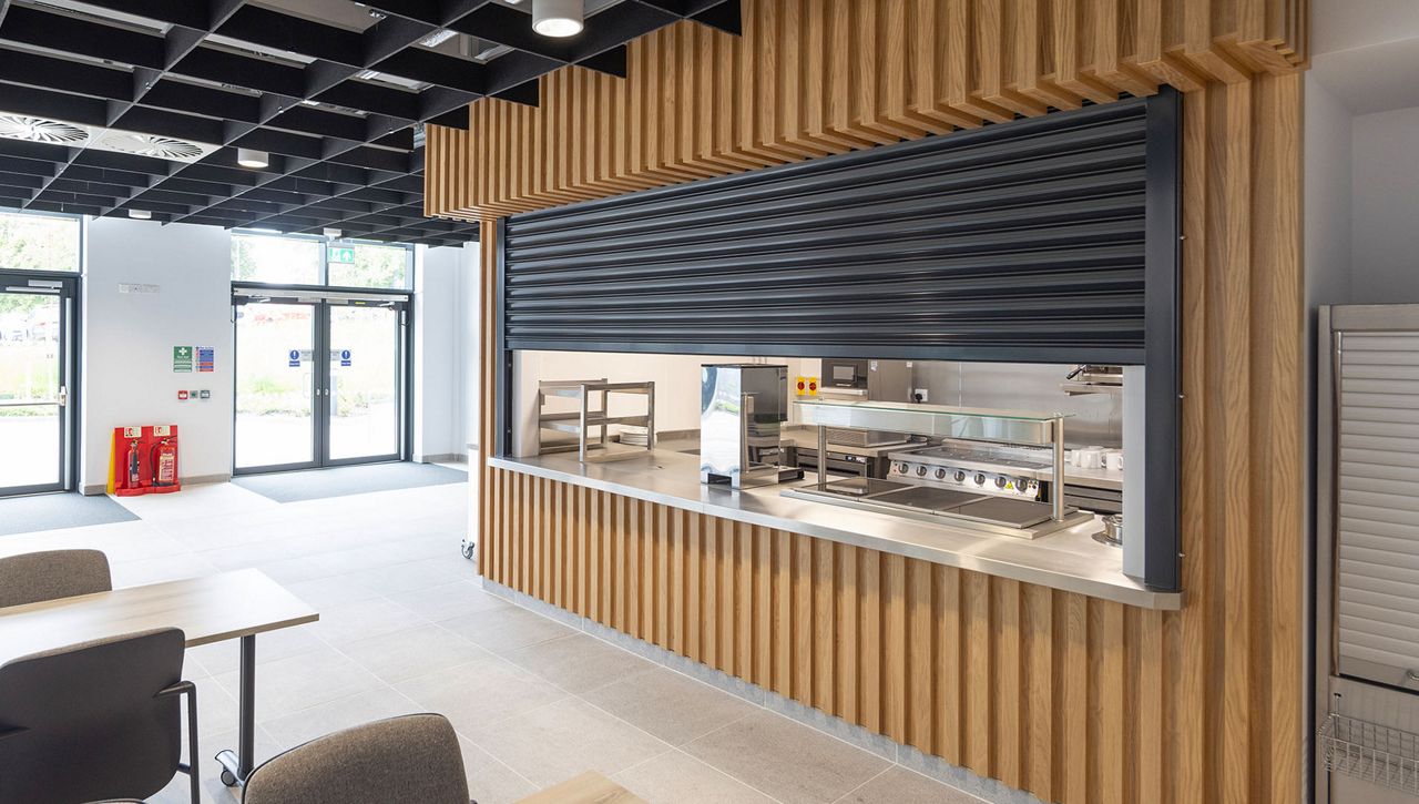 An ASSA ABLOY fire rated roller shutter, half way opened, in a canteen environment at a fire station